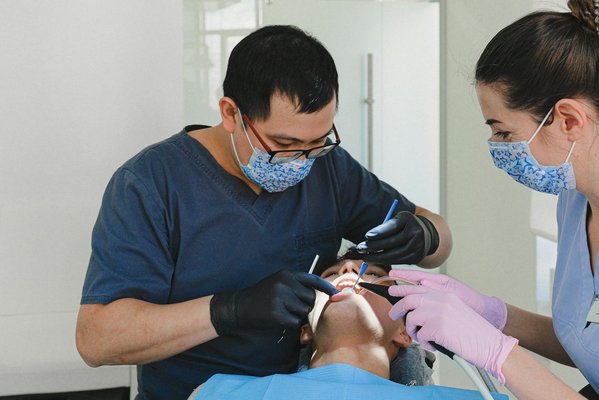 Profissionais de odontologia realizando limpeza dental (profilaxia) em paciente no consultório