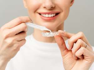 Paciente sorrindo após clareamento dental supervisionado em consultório odontológico